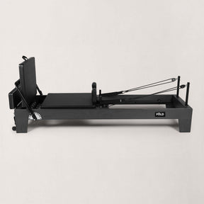 FOLD STUDIO Reformer machine in black with vegan-friendly upholstery and adjustable components.