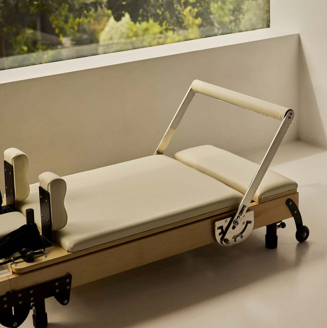 Beige FOLD Reformer bed in minimalist room with leaves in window