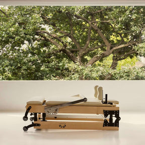 Folded FOLD Reformer bed in beige positioned in front of window with trees and leaves