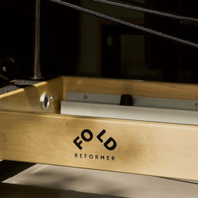 Close up of FOLD Reformer logo on wooden frame of FOLD Reformer bed