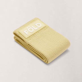 Pilates Resistance Band - Yellow Light folded with FÔLD logo, ideal for light resistance and beginner exercises.