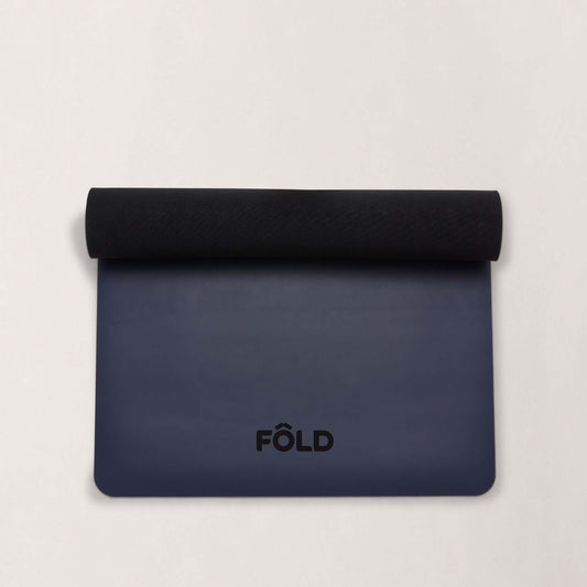 FOLD Reformer Pilates Mat - Navy laying flat with a black rolled edge, designed for comfort and stability.