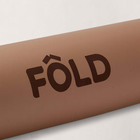 FOLD Yoga Mat - Caramel close-up showcasing the logo on a soothing caramel background.