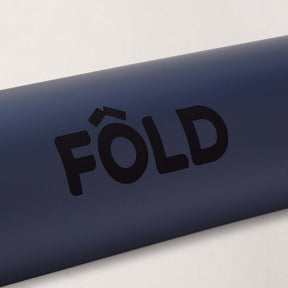 FOLD Yoga Mat - Navy close-up showing logo on a dark blue textured surface for yoga and Pilates sessions.