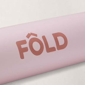 Close-up of the FOLD Yoga Mat - Pink highlighting the logo and soft surface for grip and stability.