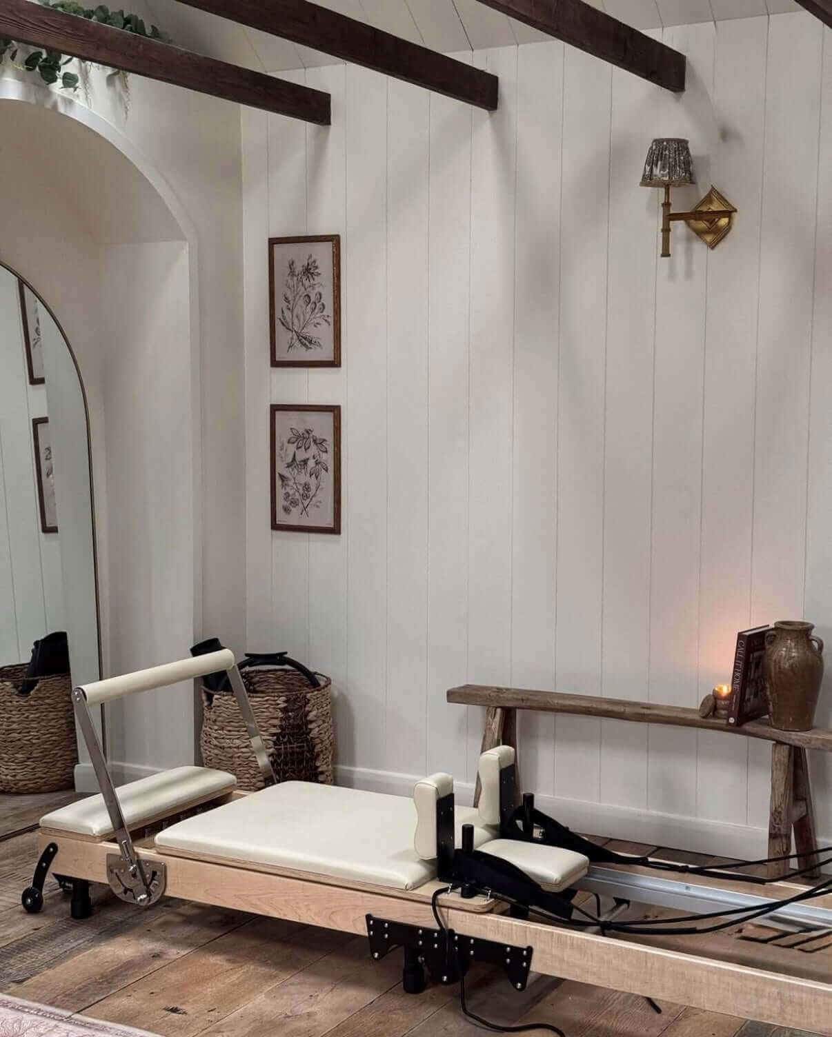Pilates reformer machine in a room with wooden floor and white walls.