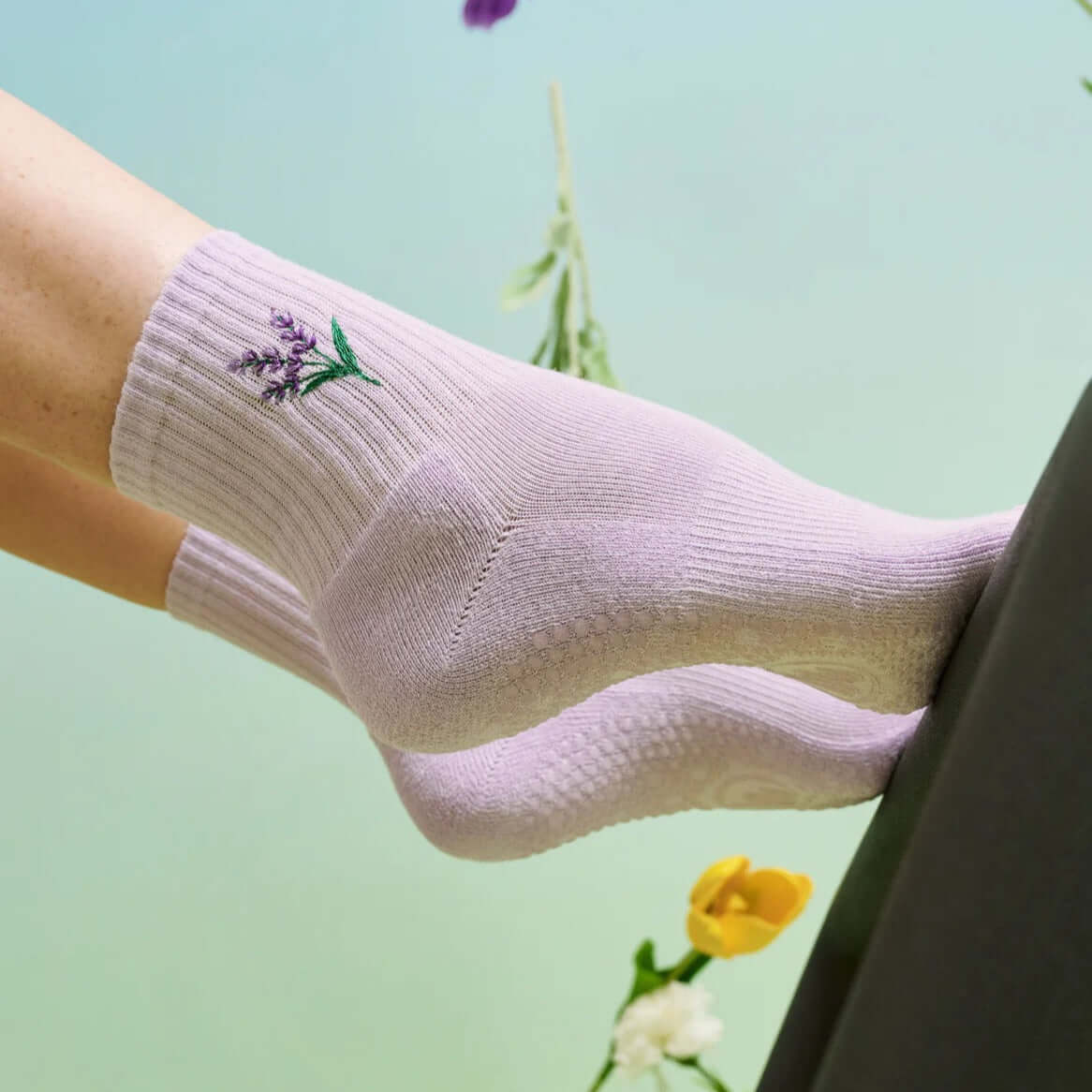 Two feet in Lavendar Haze Pilates grip socks on edge of Reformer footbar