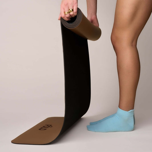 Pilates Low Rise Grip Socks - Baby Blue worn while unrolling a black yoga mat.