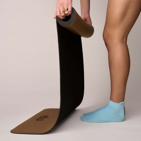 Pilates Low Rise Grip Socks - Baby Blue worn while unrolling a black yoga mat.