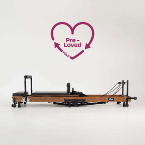 Pre-Loved Original FOLD Reformer - With Easi-Fold™ featuring a red oak frame and black upholstery.