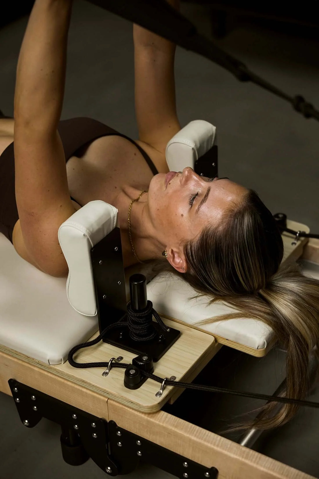 What happens in reformer pilates class? A woman practicing on a Reformer Pilates bed.