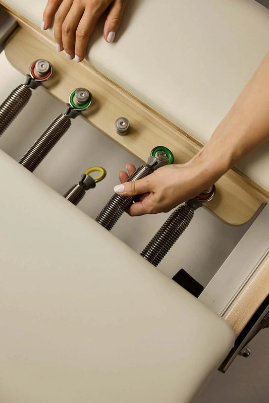 Understanding reformer spring resistance and finding the right tension for you, adjusting springs on a Pilates reformer.