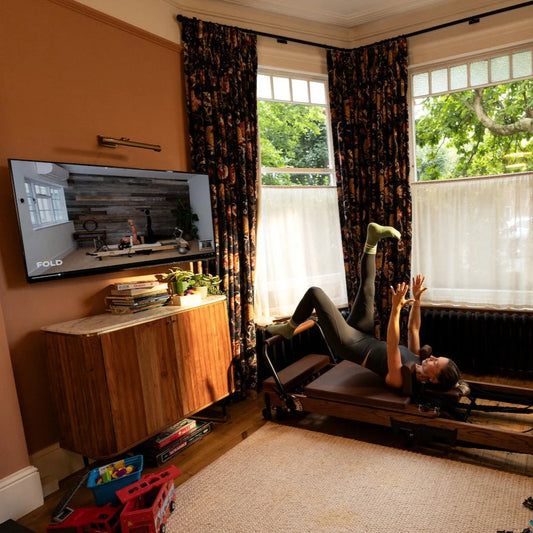 Person practicing Reformer Pilates for Rehabilitation: Rebuild Strength & Mobility in a bright living room.