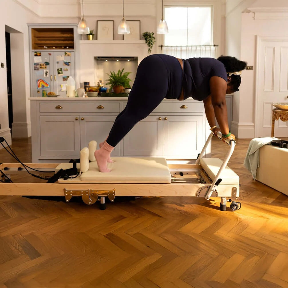 Unlock the Benefits of a Reformer Pilates Machine, a person using a reformer Pilates machine at home.