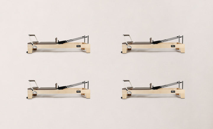 Four views of a modern Pilates reformer in light wood and dark upholstery for fitness enthusiasts.