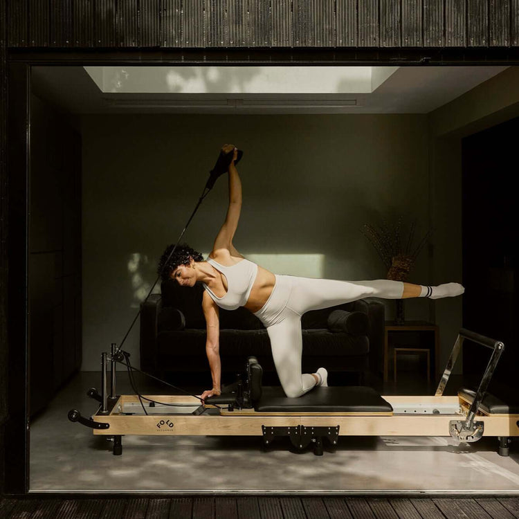 Female arm outstretched on a FOLD Reformer in a design led living room space