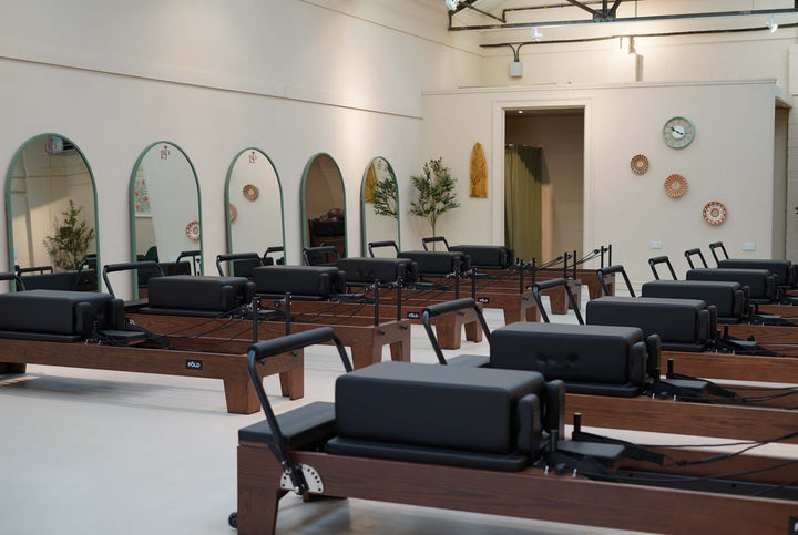 Modern Pilates studio featuring multiple reformers and mirrors in a bright, inviting space.