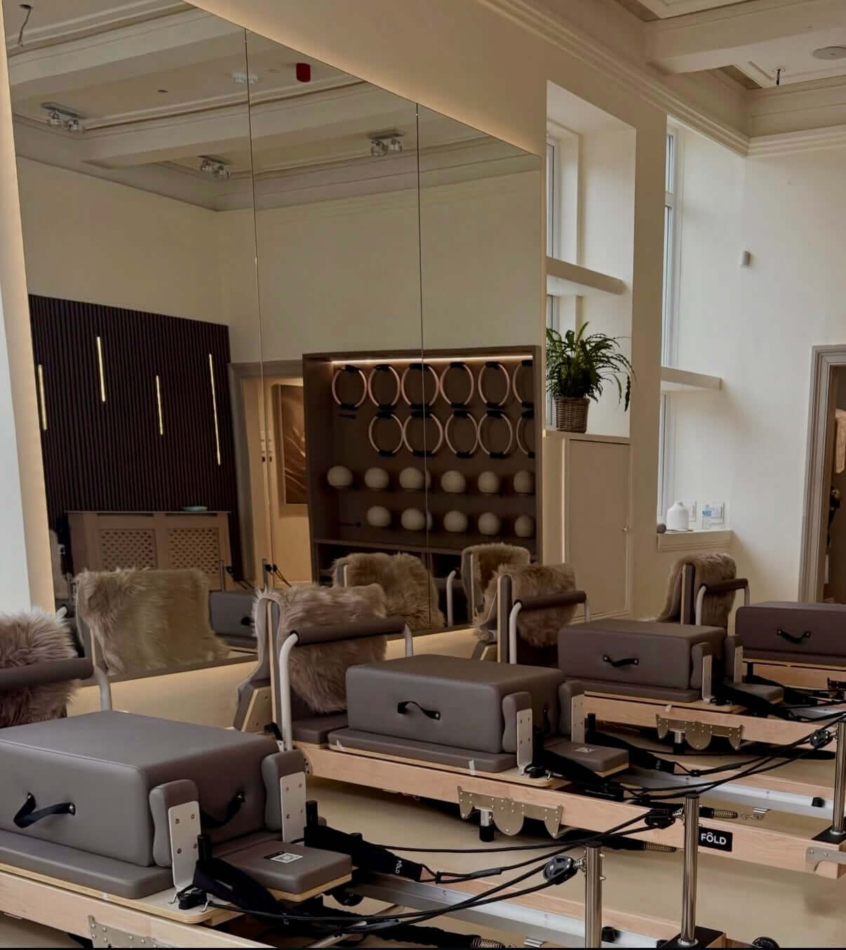 Pilates reformers in a studio with mirrors and equipment in the background