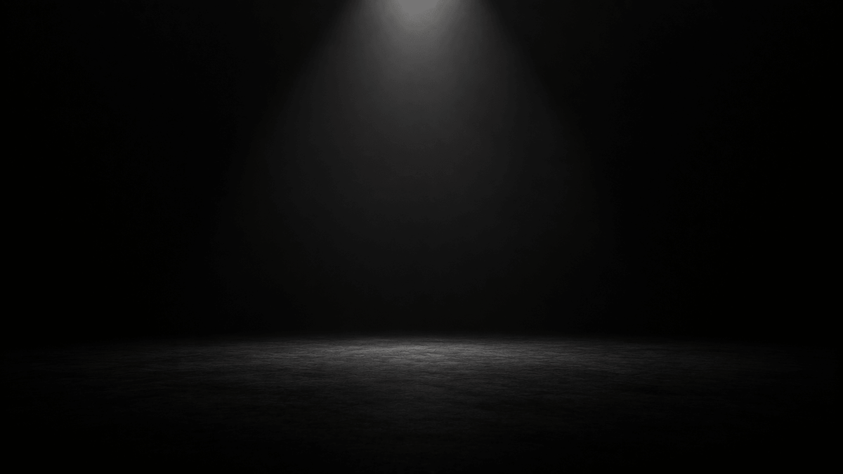 A dramatic dark stage with a single spotlight illuminating the floor, creating a mysterious atmosphere.