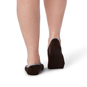 Brown slip-on shoes with textured sole worn by a person on a white background