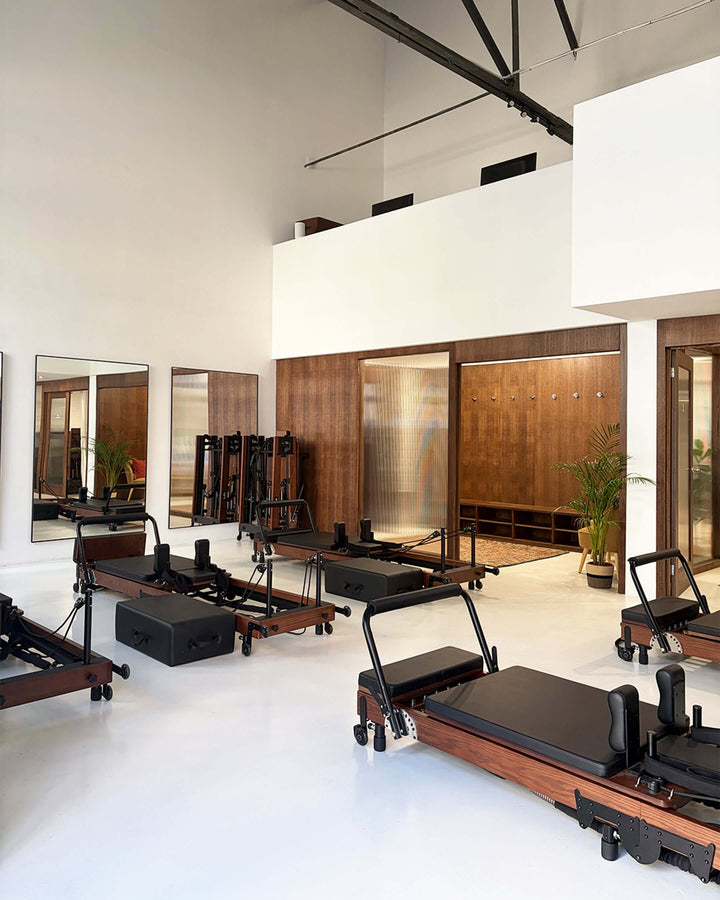 Modern Pilates studio interior featuring reformers and mirrors with a clean, bright design.