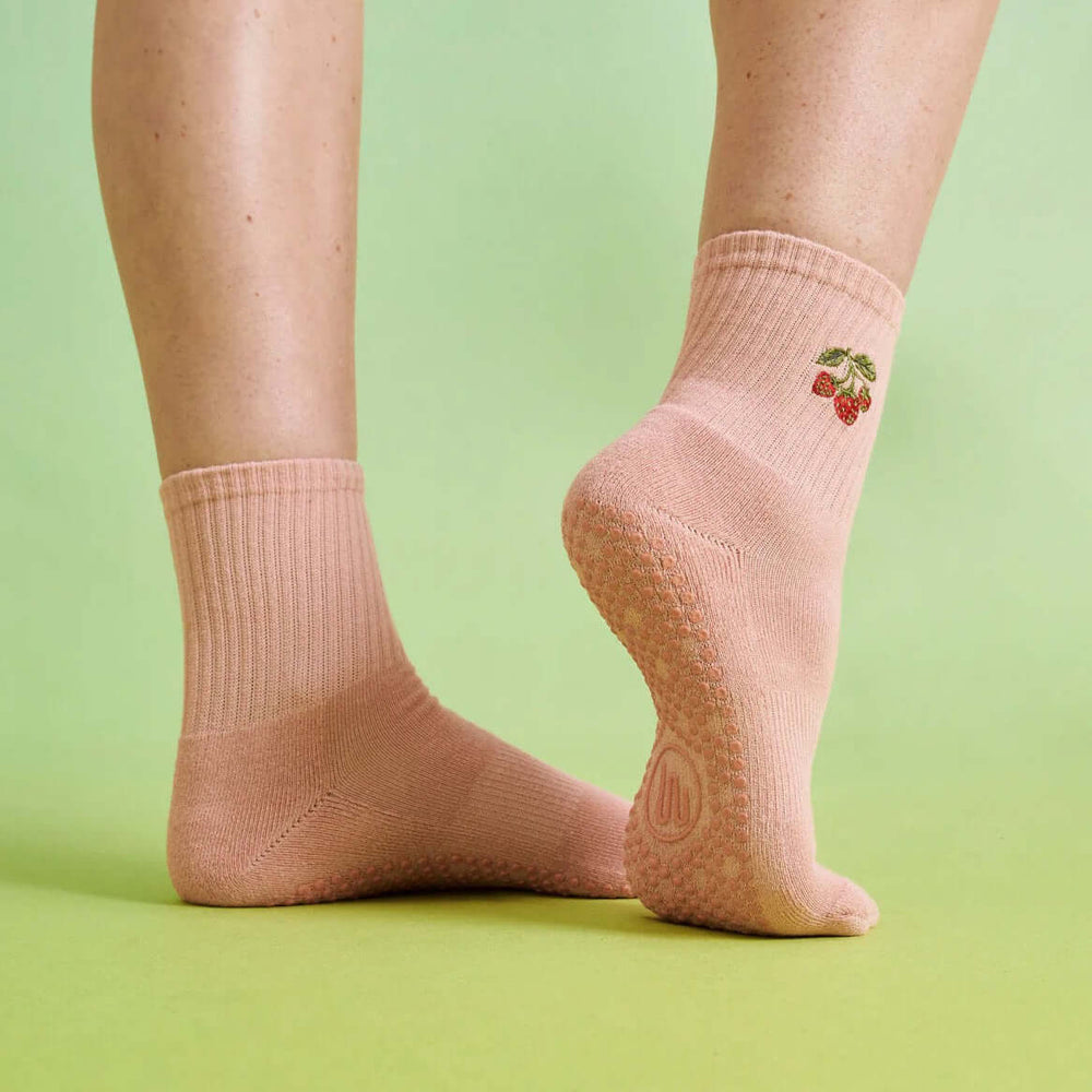 One foot at an angle wearing pair of Strawberry Patch grip socks