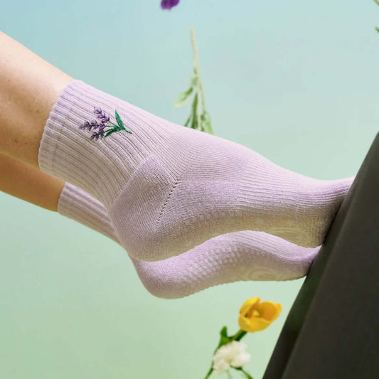 Two feet in Lavendar Haze Pilates grip socks on edge of Reformer footbar