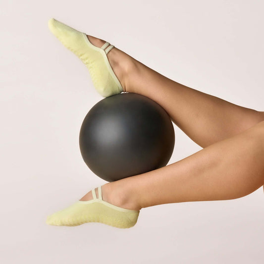 Ballet Grip Socks - Lime in use, non-slip grip sole on a black exercise ball for yoga and Pilates workouts.