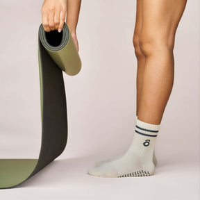 Everyday Crew Grip Socks - Forest Green worn while unrolling a yoga mat for a Pilates class.