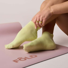 Pilates Low Rise Grip Socks - Lime worn during practice on a yoga mat, showcasing their comfort and style.