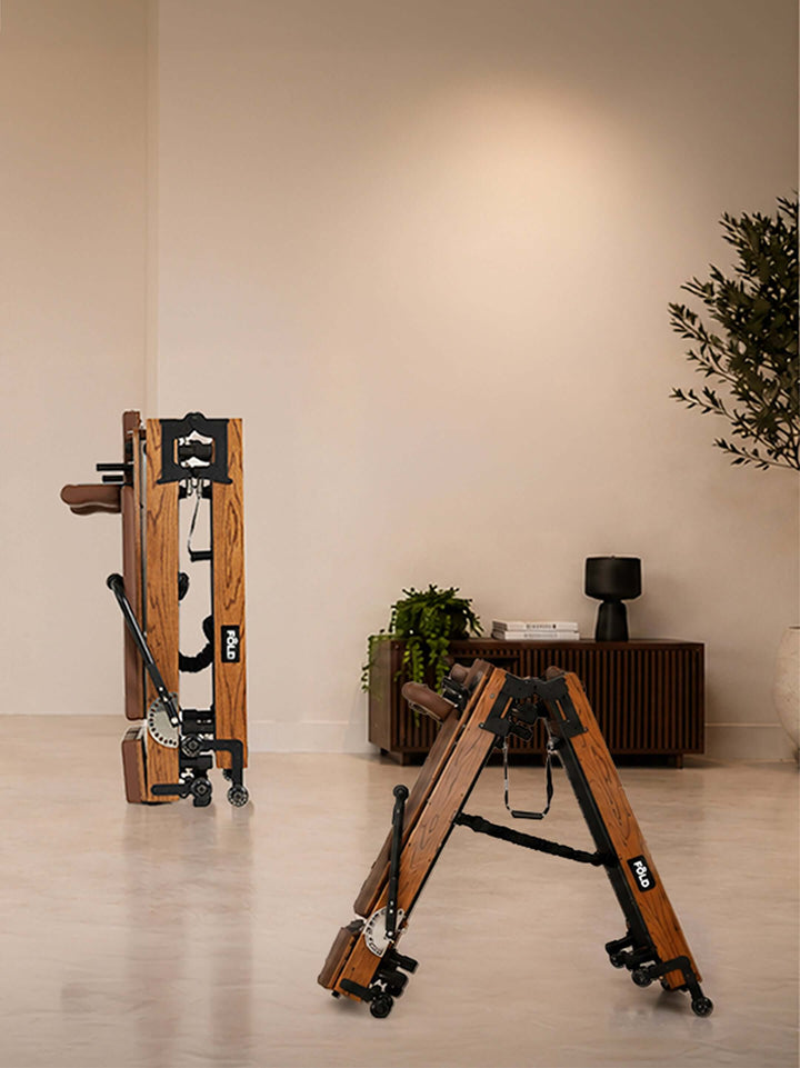 Foldable wooden fitness equipment displayed in a minimalistic room with a plant and modern furnishings.