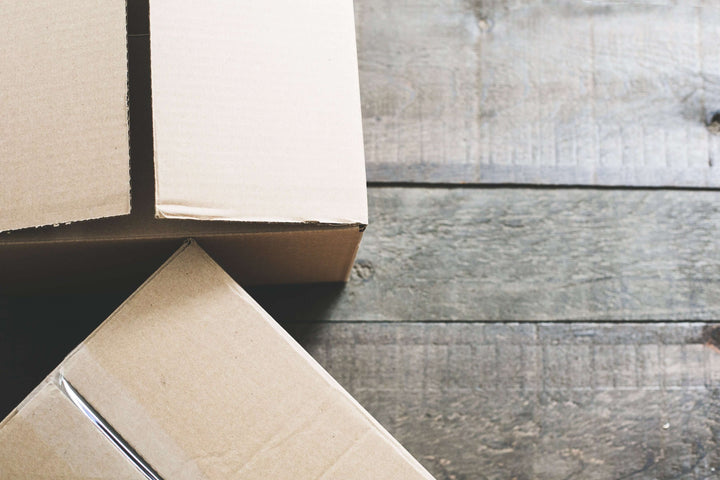 Two cardboard boxes resting on a wooden surface, showcasing their edges and textures.