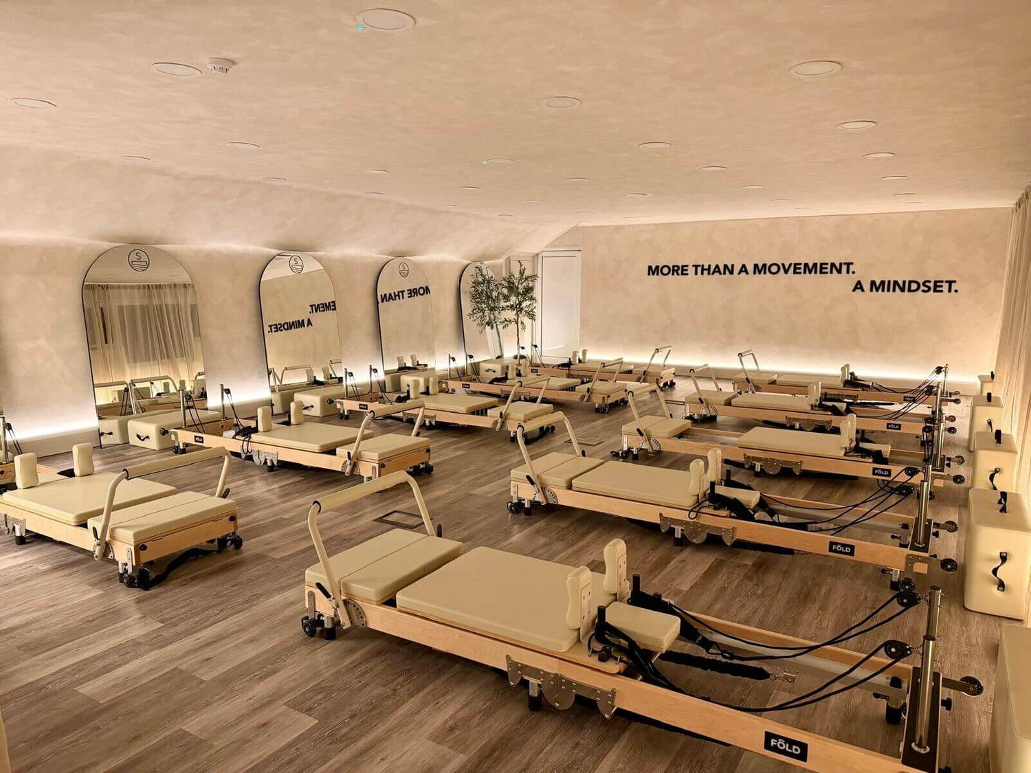 Pilates reformers in a studio with mirrors and motivational wall text.